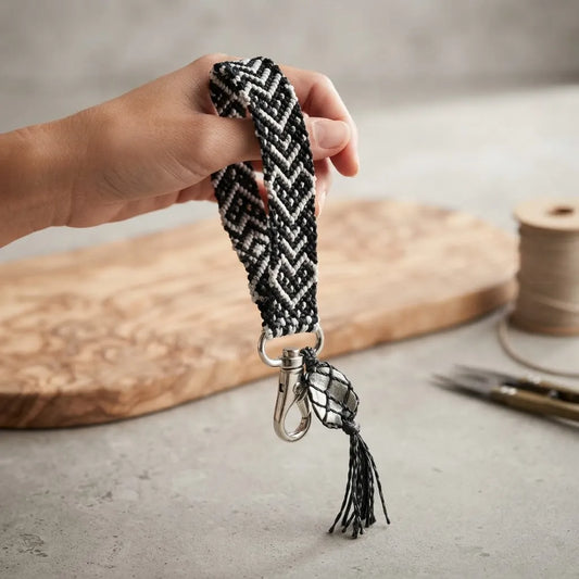 Detalle de llavero artesanal de macramé con mosquetón metálico y piedra decorativa tejida.
