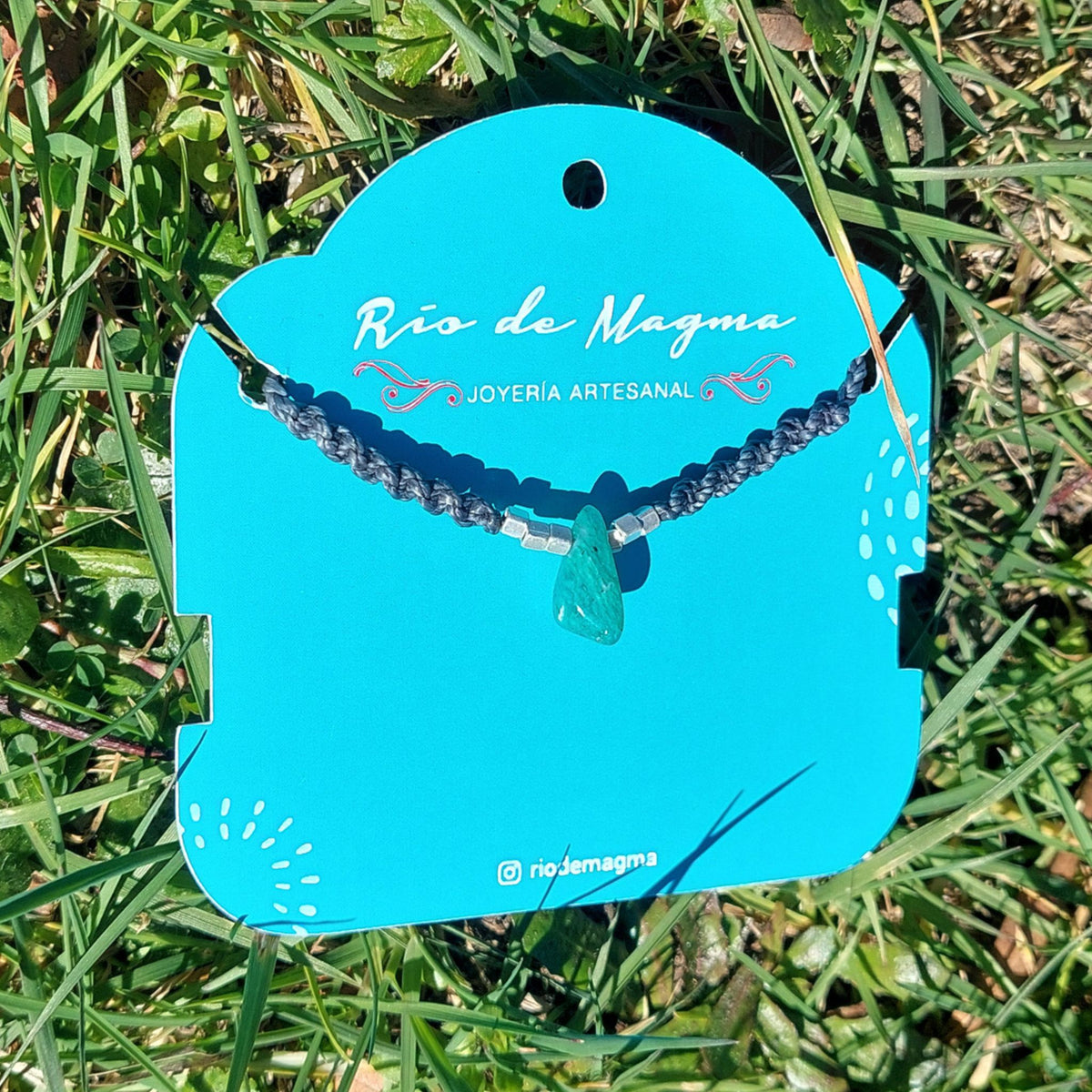 Collar Luz de amazonita natural en macramé gris con plata 950, mostrando la piedra verde agua característica de la amazonita sobre tarjeta de Río de Magma