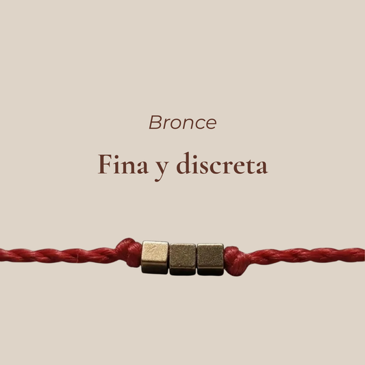 Pulsera delgada roja con cubos de bronce con texto 'Best Seller' sobre fondo beige