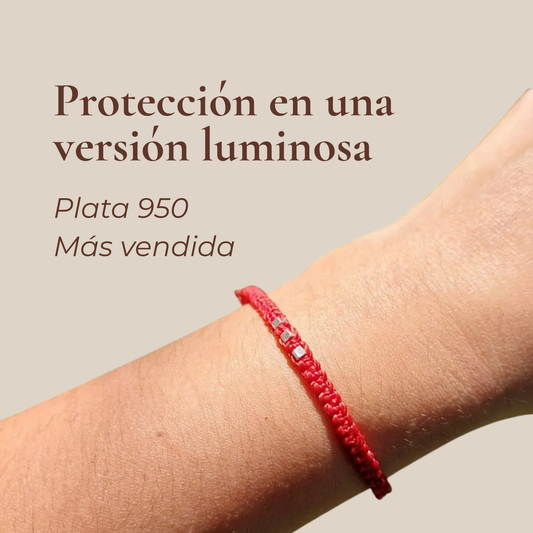 Pulsera roja de macramé con plata 950 puesta en la muñeca. Texto: "Protección en una versión luminosa".
