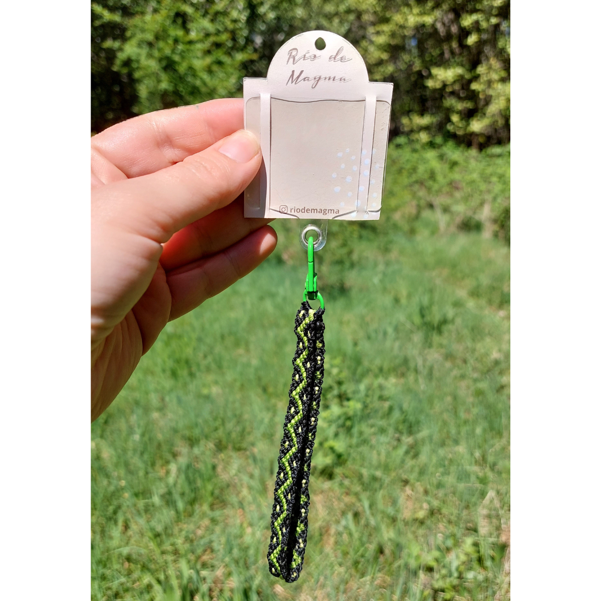 Adaptador para celular con correa artesanal de macramé verde, tejida con hilo encerado.