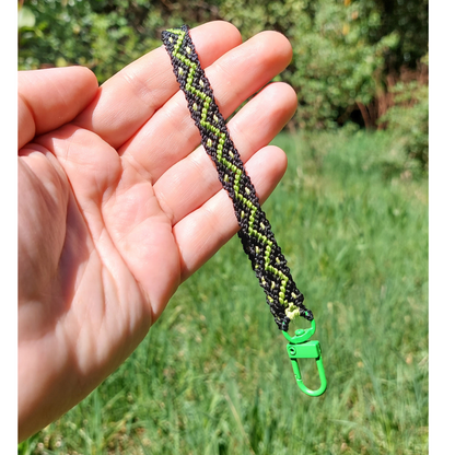 Correa para celular de macramé en tonos verdes, tejida a mano con enganche metálico verde.